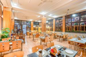a restaurant with tables and chairs and windows at Hotel Auli D in Joshīmath