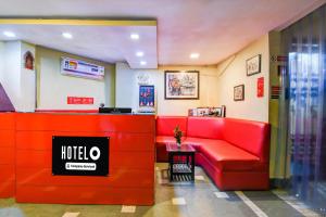 a waiting room with a red couch in a restaurant at Hotel O Alipore Near Chetla Formerly Alipore Guest House in Kolkata