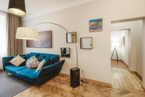 een woonkamer met een blauwe bank en een lamp bij Bearsleys Archers Apartments in Rīga