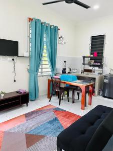 a living room with a table and blue curtains at Zara Homestay Tok Bok in Machang
