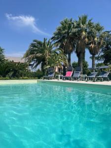 a swimming pool with chairs and palm trees at Villa Valè con piscina in Ischia