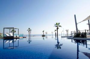 a swimming pool with palm trees in the background at Sea Senses by Mar Holidays in Torrevieja