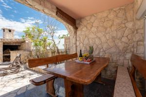 a wooden table and chairs on a patio with a stone wall at Bayview Villa by Pag tours in Pag
