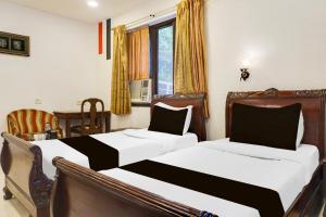 a bedroom with two beds and a window at Super Townhouse Oak Prabhat Road in Pune