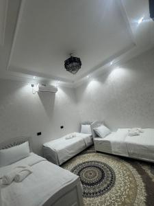 a bedroom with two beds and a rug at Abdulaziz Xostel in Samarkand