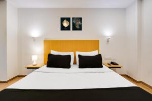 a bedroom with a large white bed with two pillows at Super Townhouse Oak Indiranagar in Bengaluru