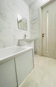 Un baño blanco con lavabo y espejo. en new apartment near the center квартира в новому будинку поруч з центром, en Sumy