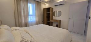 a white bedroom with a bed and a window at Luxury Furnished Apartment in Salalah Center in Salalah
