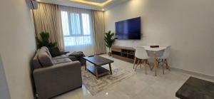 a living room with a couch and a tv and a table at Luxury Furnished Apartment in Salalah Center in Salalah