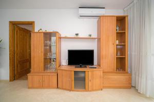 a living room with a tv and a wooden entertainment center at Coliseo Spaniahome in L’Alfàs del Pi