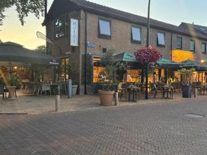 a brick building with tables and chairs and umbrellas at Hotel restaurant de Pionier in Marknesse