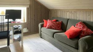 a living room with a green couch with red pillows at Cabin With Panoramic Views Over The Mountains in Nesbyen