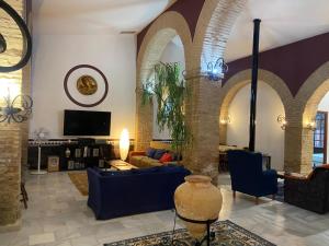 a living room with arches and a couch and a tv at Casona La Fábrica in Villalba del Alcor