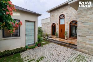 una casa con una casa de ladrillo con una puerta de madera en StayVista at Rustic Roots with Bonfire, Lawn, en Jaipur