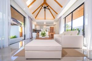 Elle comprend un salon doté d'un mobilier blanc et de grandes fenêtres. dans l'établissement Anchan Villas Phuket - Private 2 Bedroom Pool Villas by Escape Villas, à Ban Phru Champa