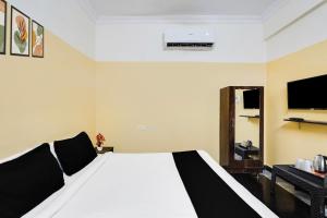 ein Schlafzimmer mit einem weißen Bett und einem Fernseher in der Unterkunft Super Hotel O Karakambadi Road Near Leela Mahal Circle in Tirupati