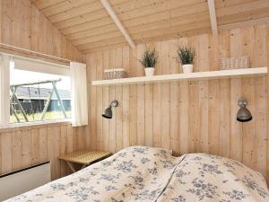 a bedroom with wooden walls and a bed and a window at Modern Beach Retreat - By Traum Ferienwohnungen in Løkken +16 photos