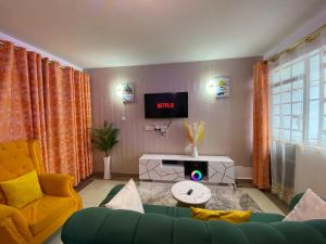 a living room with a couch and a tv at Cozy & Modern One Bedroom Opposite Garden City Mall in Nairobi