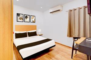 a bedroom with a bed and a desk in a room at Super Townhouse Pondicherry in Puducherry