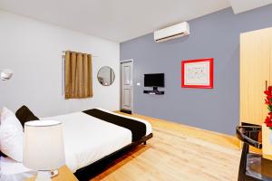 a hotel room with a bed and a tv at Super Townhouse Pondicherry in Puducherry