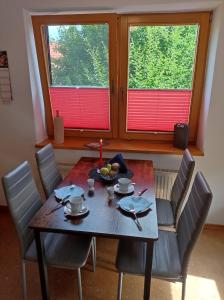 a dining room table with chairs and a table and two windows at Ferienwohnung Moder in Neuharlingersiel