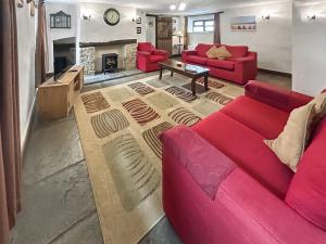 a living room with two red couches and a fireplace at Cider House in Hawkchurch