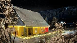 a yellow house with a red door in the snow at Tolles Ferienhaus in Oberwiesenthal