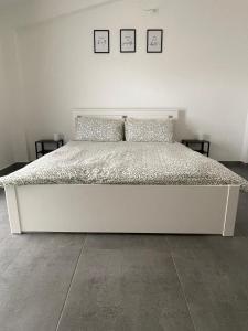 a white bed in a bedroom with two pictures on the wall at L&C hideaway in Sestu