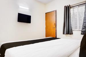 a bedroom with a bed and a tv on the wall at Super Collection O Uptown Hinjewadi in Pune