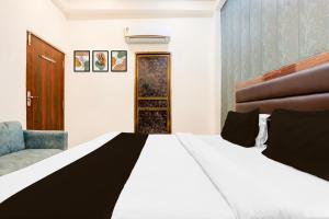 a bedroom with a large bed and a chair at Super Hotel O Sankat Mochan Gandhi Nagar in Varanasi