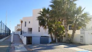 a white building with palm trees in front of it at Brisa y Mar in Calahonda