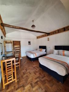 a room with two beds and a desk with a mirror at Ambokili Cottages in Kimana