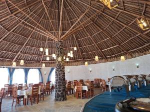 a restaurant with a straw ceiling and tables and chairs at Ambokili Cottages in Kimana +29 photos
