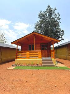 una pequeña cabaña de madera con un árbol delante en DEER COTTAGES Agonda, en Agonda