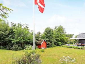 a flag pole in a yard with a red shed at 4 star holiday home in Karrebæksminde in Karrebæksminde