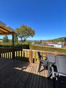 a deck with two chairs and a table and an umbrella at Houlgate - 254 - RARE VUE MER Magnifique Mobilhome 6 pers 3 chambres 2 SDB sur Camping 5 étoiles in Houlgate