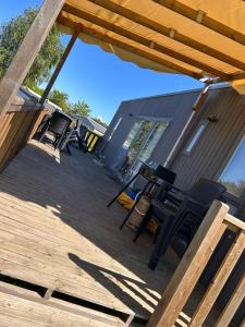 a deck with chairs and tables on a house at Houlgate - 254 - RARE VUE MER Magnifique Mobilhome 6 pers 3 chambres 2 SDB sur Camping 5 étoiles in Houlgate