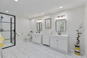 a white bathroom with two sinks and a toilet at Elegant Private Basement Apartment with Full Kitchen & Living Room in Atlanta