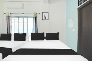 a bedroom with a large white bed with black pillows at Super Collection O Chikmangaluru Near Railway Station in Chikmagalūr +23 photos