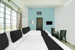 a bedroom with a large white bed and a table at Super Collection O Chikmangaluru Near Railway Station in Chikmagalūr