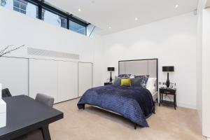 a bedroom with a bed and a desk and some windows at Urban Chic - Chiltern & Baker in London