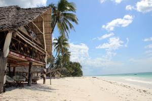 a building on the beach with palm trees and the ocean at Blu Marlin Village in Kiwengwa