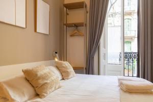 een slaapkamer met een bed met witte lakens en een raam bij The Barcelona Centric APT by Maison Piñata in Barcelona