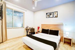 a bedroom with a large bed and a desk at Super Hotel O Katol Road Friends Colony in Nagpur