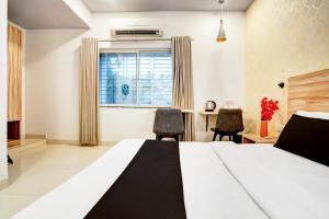 a bedroom with a bed and two chairs and a desk at Super Hotel O Katol Road Friends Colony in Nagpur