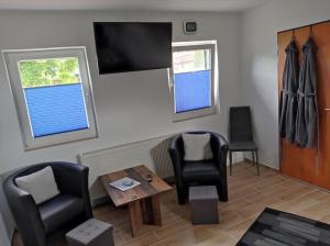 a living room with chairs and a table and a tv at Haus Morgenstern Fewo Ünnern in Neuharlingersiel