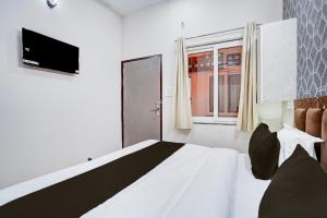 a bedroom with a bed and a television and a window at Super Townhouse Vasundra Nagar Formerly Joystel in Jaipur +27 photos