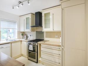una cucina con mobili bianchi e un frigorifero di Mill Cottage ad Aberdyfi