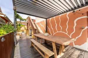 a wooden picnic table on a patio with awning at La Boga, un havre de paix en plein coeur de Biscarrosse Plage in Biscarrosse-Plage +1 photo