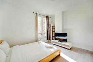 a white room with a bed and a tv at La Bella - 4 Prs - Porte de Paris - WiFi in Asnières-sur-Seine